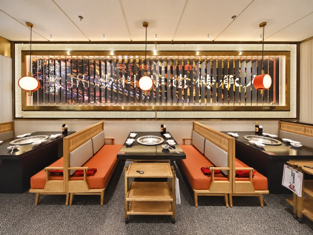 Booth seating and hotpot tables in a coordinated warm palette.