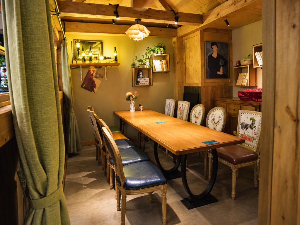 Private dining room with long wood restaurant table and mixed vintage chairs.