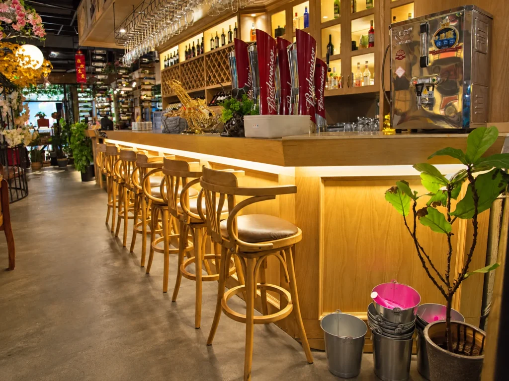 Restaurant bar counter area with wood bar stools and warm lighting.
