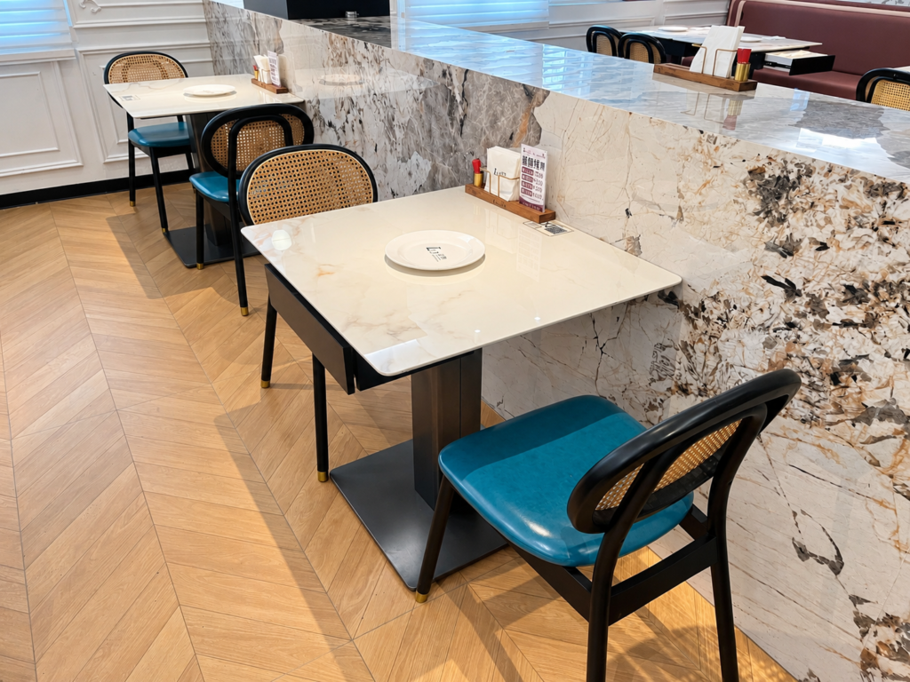 Restaurant dining table and chair layout beside the marble-look wall.